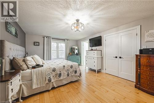 Bedroom with light wood-finish flooring, a tufted fabric headboard, a window with curtains, and white bi-fold closet doors - 70 Webster Road, Hamilton, ON 