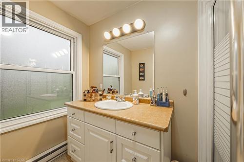 Bathroom vanity featuring a single basin sink, laminate countertop, and white cabinetry - 70 Webster Road, Hamilton, ON 