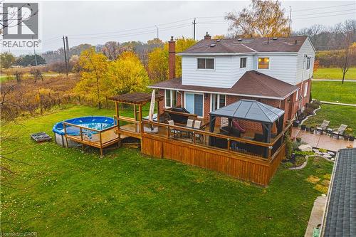 Expansive backyard featuring a multi-level wood-finish deck with a pergola, an above-ground swimming pool, and a dedicated patio area - 70 Webster Road, Hamilton, ON 