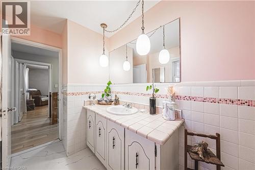 Bathroom vanity featuring a single basin, tiled countertop, and suspended pendant lighting - 70 Webster Road, Hamilton, ON 