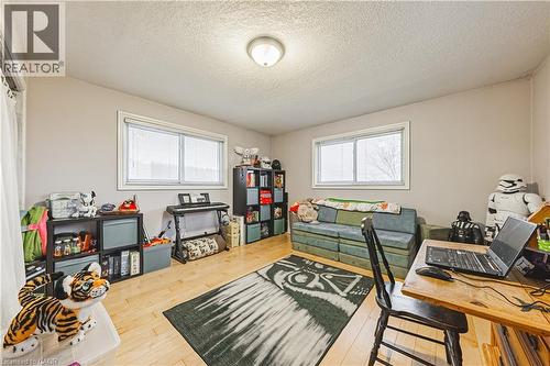 Spacious room featuring light wood-finish flooring, two large windows with white blinds, and neutral painted walls - 70 Webster Road, Hamilton, ON 