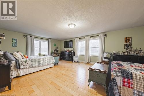 Spacious interior with light wood-finish flooring, multiple windows, and light green painted walls - 70 Webster Road, Hamilton, ON 