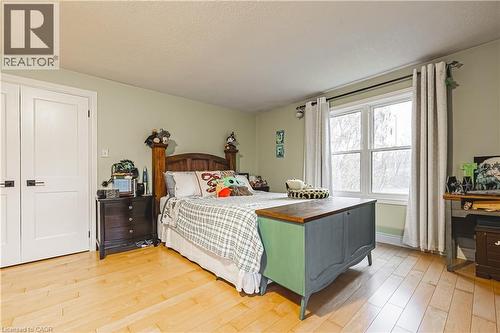 Light wood-finish flooring with a multi-pane window, white trim, and light green walls - 70 Webster Road, Hamilton, ON 
