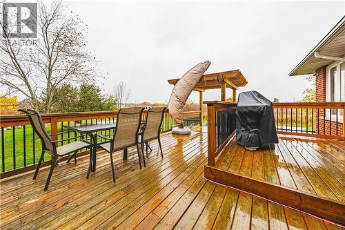 Expansive wood deck featuring a natural wood finish, black metal balusters, and a built-in pergola structure - 70 Webster Road, Hamilton, ON 