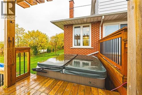 Expansive wood-finish deck featuring a built-in spa, pergola structure, and wood railing with black spindles - 70 Webster Road, Hamilton, ON 