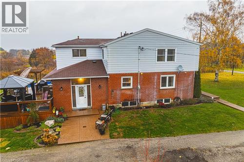 Red brick and light-colored siding exterior featuring multiple windows, a prominent entry door with decorative glass, and a covered front porch - 70 Webster Road, Hamilton, ON 