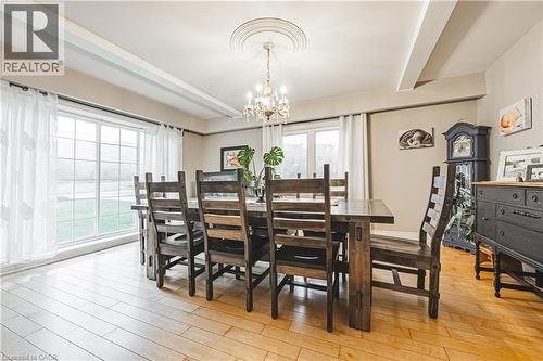 Spacious room featuring wood-finish flooring, a large multi-pane window, ceiling beams, and a decorative chandelier - 70 Webster Road, Hamilton, ON 