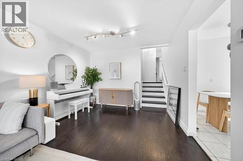 Open-concept living area featuring dark wood-finish flooring, white walls, and track lighting - 19 Glen Forest Drive, Hamilton, ON 