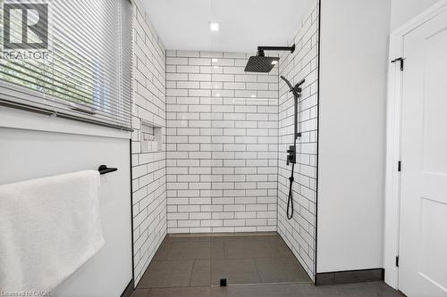 Contemporary shower enclosure featuring white subway tile walls and dark floor tiling - 19 Glen Forest Drive, Hamilton, ON 