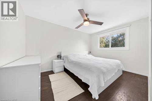 Bedroom featuring dark wood-finish flooring, a white window frame, and a ceiling fan with integrated lighting - 19 Glen Forest Drive, Hamilton, ON 