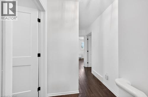 Crisp white walls define this interior hallway, featuring dark wood-finish flooring - 19 Glen Forest Drive, Hamilton, ON 