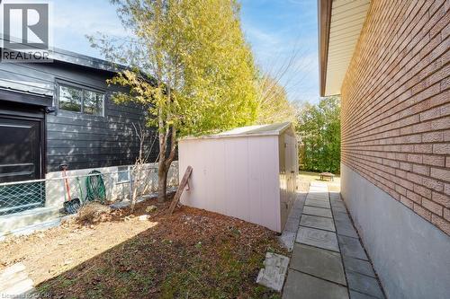 Side yard featuring a paver pathway, brick exterior, and a detached storage shed - 19 Glen Forest Drive, Hamilton, ON 