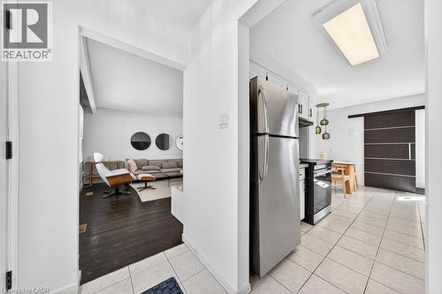 Kitchen with tile flooring and stainless steel refrigerator, featuring a contemporary pendant light fixture - 19 Glen Forest Drive, Hamilton, ON 