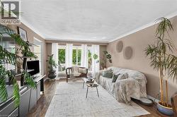 Living area featuring wood-finish flooring, light-toned walls, and white crown molding - 