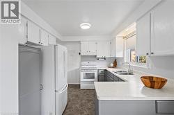 Bright kitchen featuring white upper cabinetry, gray lower cabinetry, and light-toned countertops - 