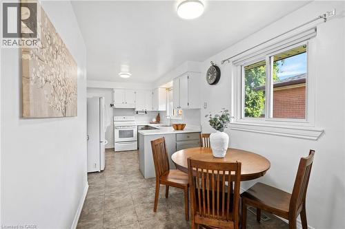 Bright kitchen featuring white cabinetry, white appliances, a window, and tile flooring - 1083 Melton Drive, Mississauga, ON 
