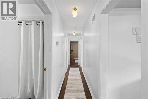 Hallway featuring dark wood-finish flooring, white walls, and flush-mount lighting fixtures - 1083 Melton Drive, Mississauga, ON 