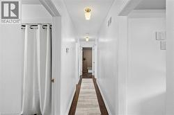 Hallway featuring dark wood-finish flooring, white walls, and flush-mount lighting fixtures - 