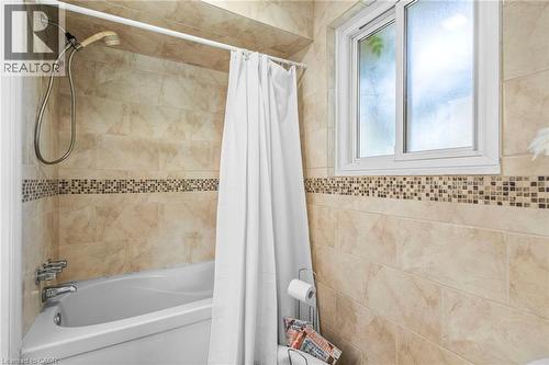 Bathtub-shower combination featuring a tiled surround with a decorative mosaic accent band - 1083 Melton Drive, Mississauga, ON 