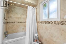 Bathtub-shower combination featuring a tiled surround with a decorative mosaic accent band - 