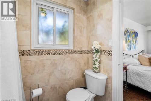 Tiled bathroom featuring a sliding window, a toilet, and a decorative mosaic tile accent - 1083 Melton Drive, Mississauga, ON 