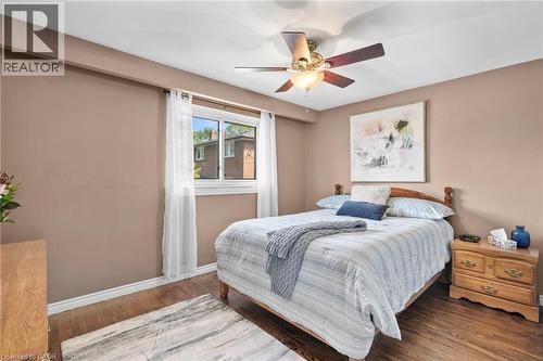 Bedroom featuring wood-finish flooring, a ceiling fan with integrated lighting, and a window with white trim - 1083 Melton Drive, Mississauga, ON 