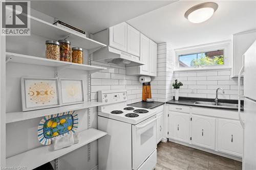 Basement Kitchen  with subway tile backsplash, white cabinetry, dark countertops, a double basin stainless steel sink, and wood-finish flooring - 1083 Melton Drive, Mississauga, ON 