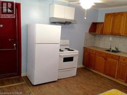 Kitchen featuring wood-finish flooring, light blue walls, and a white ceiling fan - 