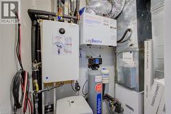 Utility area featuring a tankless water heater, water softener system, and HVAC unit - 