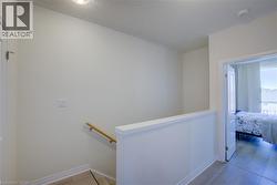 Upper landing featuring light wood-finish flooring, white wall paneling, a light wood handrail, and a white interior door frame - 