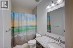 Bathroom featuring a vanity with a light granite countertop and undermount sink, a large wall-mounted mirror, and a three-light fixture - 
