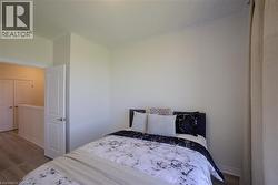 Bedroom featuring neutral wall tones, crown molding, and wood-finish flooring - 