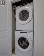 Dedicated laundry closet featuring a white stacked washer and dryer unit - 