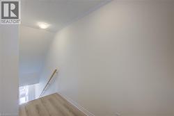 Stairwell featuring light wood-finish flooring, a light wood handrail, and a flush-mount ceiling light fixture - 