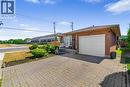 Brick-clad single-story residence featuring an attached garage with a white panel door, a paved driveway, and a concrete front porch - 102 Juniper Drive, Hamilton, ON 