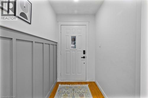 Entryway featuring rich wood-finish flooring, white walls, and a paneled accent wall - 102 Juniper Drive, Hamilton, ON 