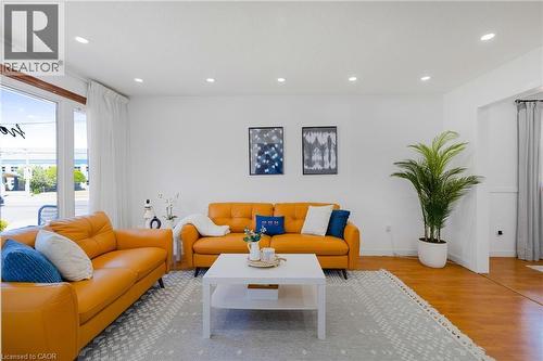 Living area featuring wood-finish flooring, recessed lighting, and a large window with white curtains - 102 Juniper Drive, Hamilton, ON 