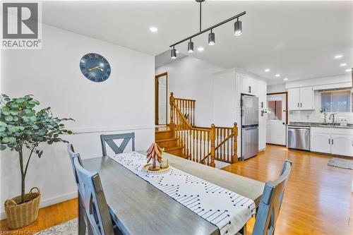 Open-concept dining area featuring wood-finish flooring, a contemporary track light fixture, and white wall finishes - 102 Juniper Drive, Hamilton, ON 