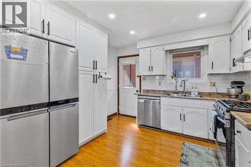 Kitchen featuring white cabinetry with dark hardware, a stainless steel refrigerator, and wood-finish flooring - 102 Juniper Drive, Hamilton, ON 