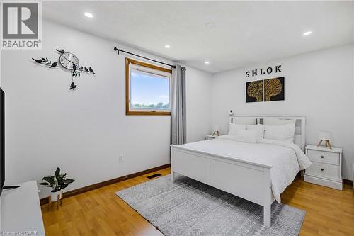 Wood-finish flooring throughout, featuring a window with wood trim and a neutral curtain - 102 Juniper Drive, Hamilton, ON 
