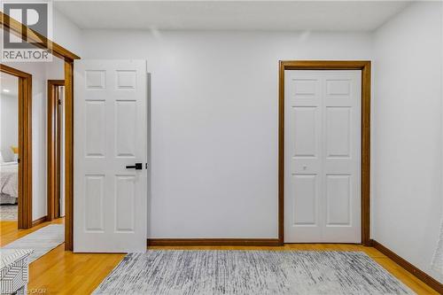 White paneled doors with dark hardware, natural wood trim, light wood-finish flooring, and white walls - 102 Juniper Drive, Hamilton, ON 