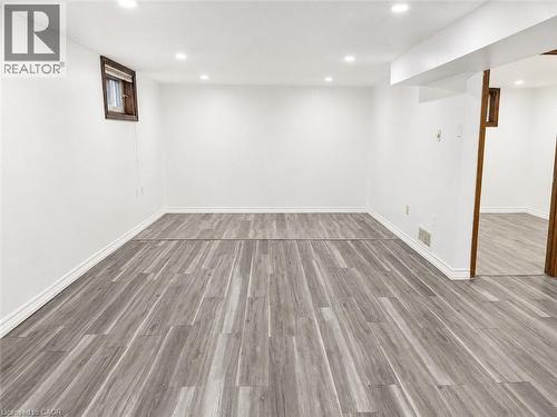 Spacious room featuring light wood-finish flooring, white baseboards, and bright recessed lighting - 102 Juniper Drive, Hamilton, ON 