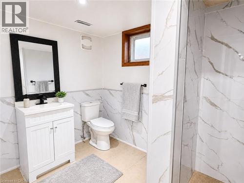 Contemporary bathroom featuring a white vanity with a black faucet, a framed mirror, and a toilet - 102 Juniper Drive, Hamilton, ON 