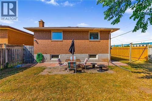 Expansive backyard featuring a brick exterior, a concrete patio, and a wood privacy fence - 102 Juniper Drive, Hamilton, ON 