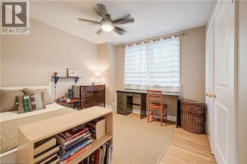 Bedroom featuring a ceiling fan with integrated lighting, wood-finish flooring, a window with horizontal blinds, and a built-in closet with double doors - 314 Glasgow Street, Kitchener, ON 