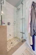 Glass-enclosed shower featuring subway tile walls and a pebble-tiled floor - 