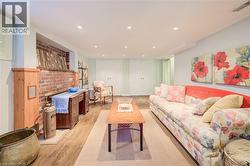 Finished lower level featuring recessed lighting, wood-finish flooring, a brick-front fireplace, and white paneled double doors - 