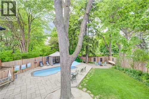 Expansive backyard with a swimming pool, surrounding patio pavers, and a fire pit area - 314 Glasgow Street, Kitchener, ON 