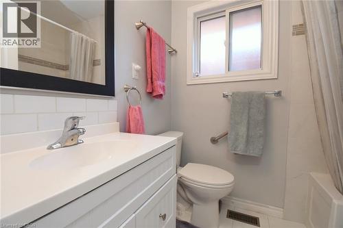 Bathroom featuring a white vanity with integrated sink, chrome faucet, and subway tile backsplash - 185 Rosslyn Avenue N, Hamilton, ON 
