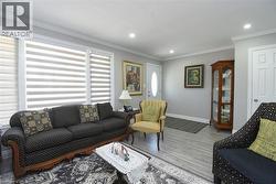 Spacious living area featuring light wood-finish flooring, recessed lighting, and crown molding - 